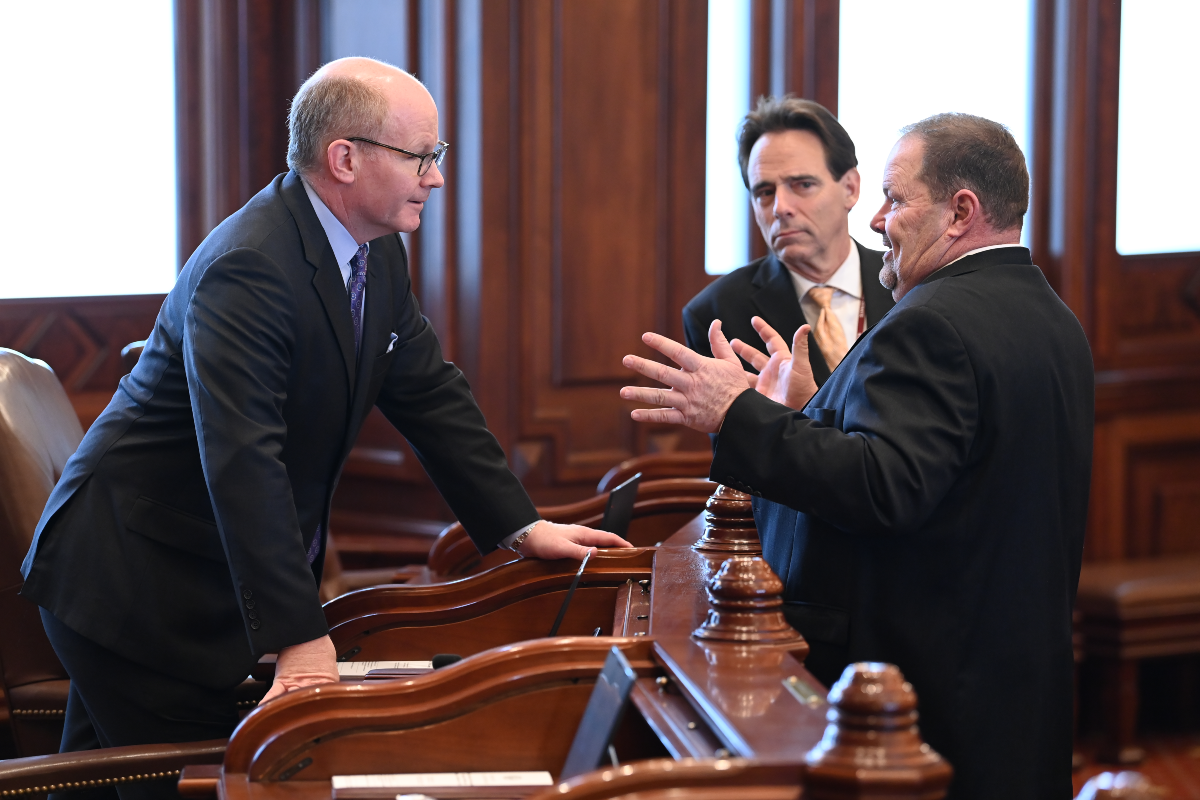 President Harmon, Senator Joyce, and Senator Stadleman speak to each other in the Senate Chamber.