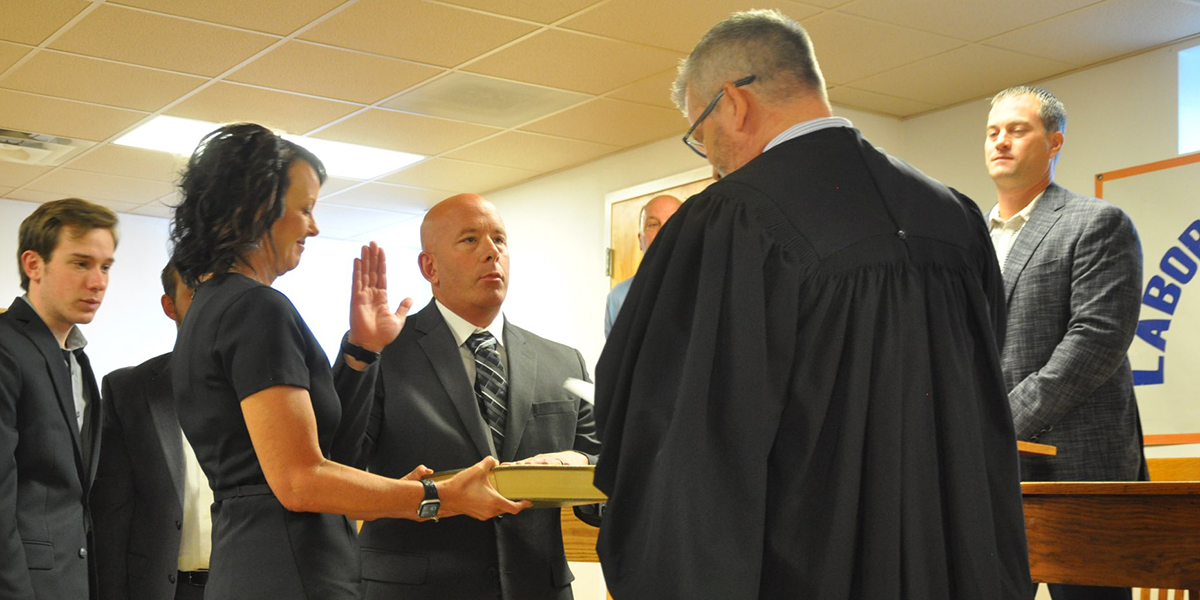 Surrounded by his wife, Jaime, and two sons, Kris Tharp (D-Bethalto) takes the oath to represent Illinois’ 56th Senate District in Wood River on Friday, July 8.